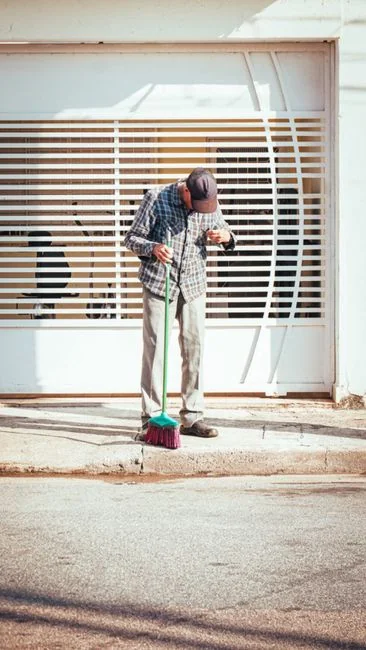 A worker cleaning skyscraper windows with a harness in an urban setting.